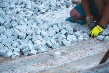 Man hand worker. stone pavement, construction worker laying cobblestone rocks on sand, tile...