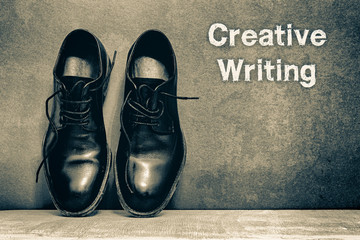 Creative Writing on brown board and work shoes on wooden floor