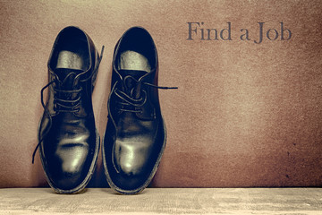 Find a Jobt on brown board and work shoes on wooden floor