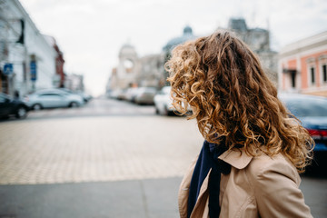 Fototapeta na wymiar Young woman in a beige coat with curly hair