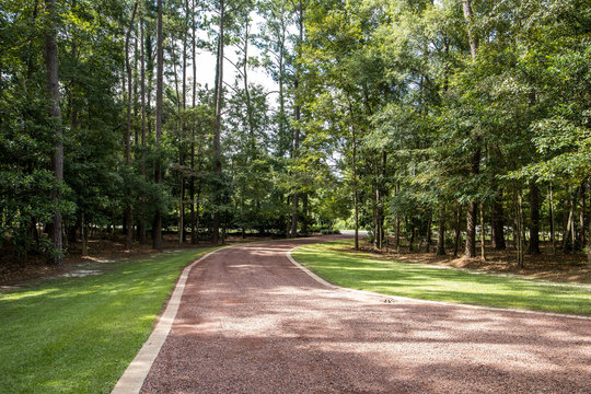 long gravel driveway which leads to a house secluded in trees