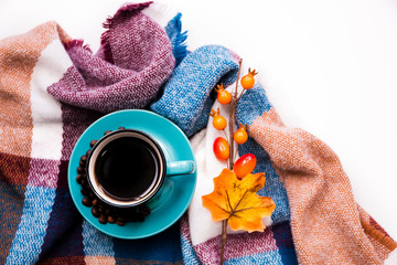 blue instant coffee Cup on saucer and beans on warm cozy plaid on white background close up, copy space top view flat lay, autumn mood