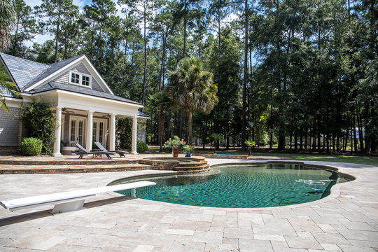 Custom pool House behind a landscaped estate with a large swimming pool and hot tub