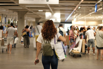 Shopping girl in a mall. she carries a green backpack and a reusable shopping bag and a cell phone