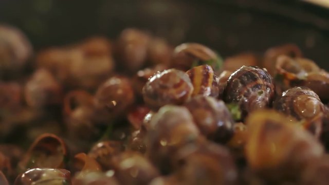 Cook stirring a pot of cooking snails