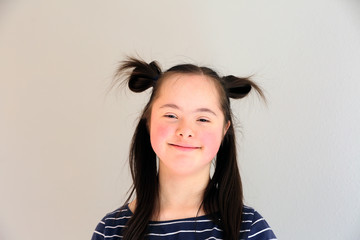 Cute smiling down syndrome girl on the grey background