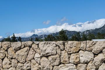 Brick fence with the mountains on the background, stone fence closeup with the mountain and forest landscape - Image