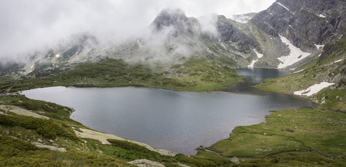 Panorama of misty, moody, dramatic weather above beautiful Twin glacial lake on Rila mountain in Bulgaria