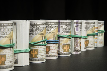 A lot of dollars money rolled up in a tube, on a black background