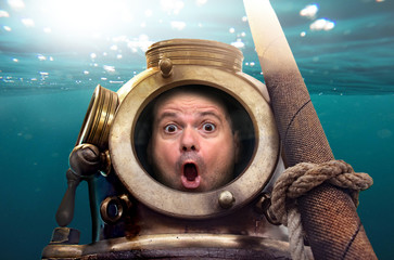 Portrait of man in old diving suit and helmet under water. Funny shocked diver in retro equipment...