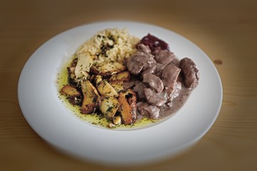 a delicious meal is roasted boletus edulis, venison goulash with rice and sauce