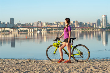 Panoramic city view in clear morning with sporty girl and bicycle on foreground
