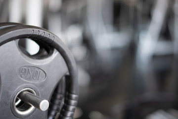 Closeup a part of weight barbell 10 kg hanging on a bar in background is a gym. Part equipment for workout at fitness room for losing weight training.