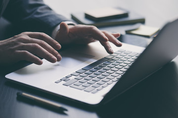 Businessman is using laptop and analysing the financial information at his office. Close up of male hands typing on computer keyboard