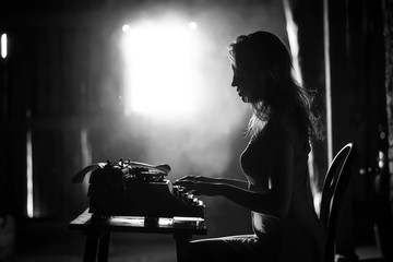 Fototapeta na wymiar A girl prints on an old typewriter