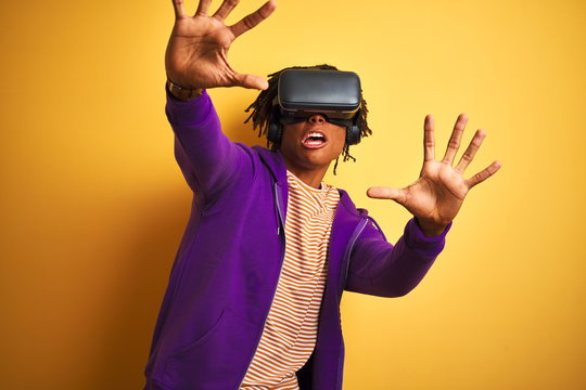 Young african american man playing virtual reality game using goggles