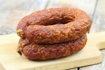 Traditional Polish smoked sausage on wooden board, closeup