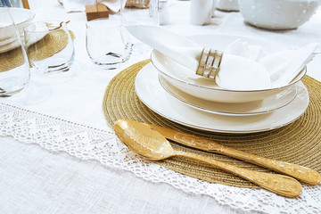 Luxury table setting - golden cutlery and plates with napkin on white tablecloth in close-up