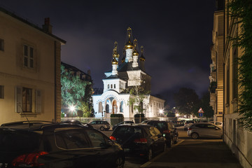 Fototapeta na wymiar Geneva street with parked cars and Russian orthodox church (Eglise Russe) at night time, Geneva, Switzerland