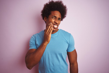 Fototapeta na wymiar African american man with afro hair wearing blue t-shirt standing over isolated pink background touching mouth with hand with painful expression because of toothache or dental illness on teeth. 