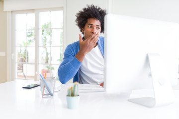African American man working using computer cover mouth with hand shocked with shame for mistake,...