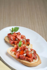 Toasted bread with sausage, presentation of catering for celebration. Served on colored tablecloth.