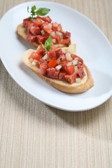 Toasted bread with sausage, presentation of catering for celebration. Served on colored tablecloth.
