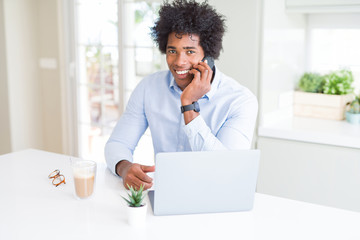 African American business man talking on the phone with a happy face standing and smiling with a confident smile showing teeth