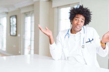 African American doctor man at the clinic clueless and confused expression with arms and hands...