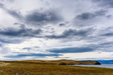 Fototapeta premium Lake Baikal, trees and mountains of Siberia with beautiful sky and clouds, Russia Oklhon island