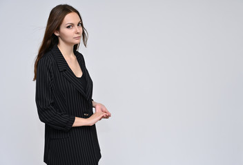 Portrait of a cute brunette girl, a young woman with beautiful curly hair in a black jacket on a white background. Smiling, talking with emotions, showing hands to the sides.