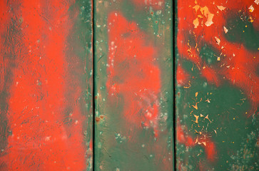 Weathered vibrant  layered green and red cracked paint on metal