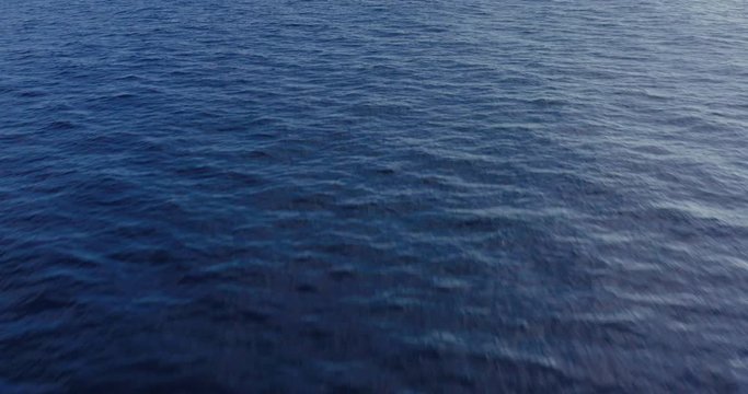Aerial drone shot flying fast and low over the ocean's blue surface capturing beautiful ocean texture