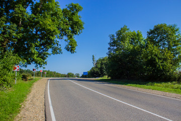 Road in a rural area with trees and blue sky