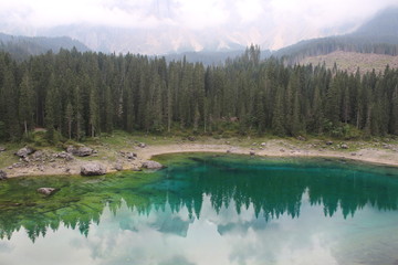 Lake Carezza, mountain lake famous for the dark green color and the beautiful panorama of mountains in the background. Reflection of the Rose Garden in the Lake. South Tirol, Italy