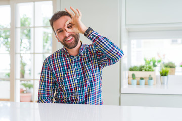 Handsome man wearing colorful shirt doing ok gesture with hand smiling, eye looking through fingers with happy face.