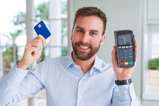 Handsome business man holding pos terminal and credit card, buying and payment using dataphone