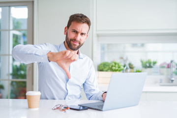 Handsome man working using computer laptop and drinking a cup of coffee with angry face, negative sign showing dislike with thumbs down, rejection concept