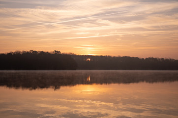 Golden Autumn Sunrise Over a Misty Calm Lake with Trees and Reflections