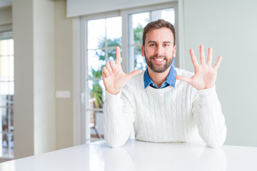 Handsome man wearing casual sweater showing and pointing up with fingers number seven while smiling confident and happy.