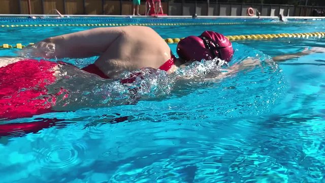 Athletic Young woman professional triathlon swimmer practicing freestyle at morning pool slow motion shot