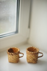two wicker mugs on the white window sill