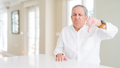 Fototapeta premium Handsome senior man at home looking unhappy and angry showing rejection and negative with thumbs down gesture. Bad expression.