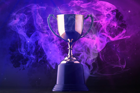 Trophy on smoke on dark blue futuristic background for e-sport winner concept.
