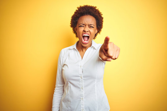 African american business woman over isolated yellow background pointing displeased and frustrated to the camera, angry and furious with you