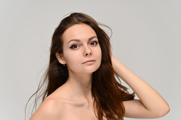 Fototapeta premium Close-up Portrait of a cute brunette girl, a young woman with beautiful curly hair and beautiful face skin. Beauty, brightness, smile, health.