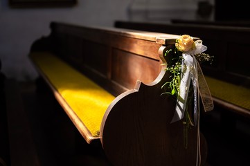 a church bench decorated with a rose for a wedding