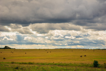 Fototapeta na wymiar A cloudy overcast sky over a field of hay bales