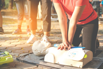 Asian female or runner woman training CPR demonstrating class in park by put hands and interlock...