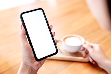 Close up view of Mockup image white screen smartphone on woman's hand. Blank copy space screen for your advertising text message or promotional content.
